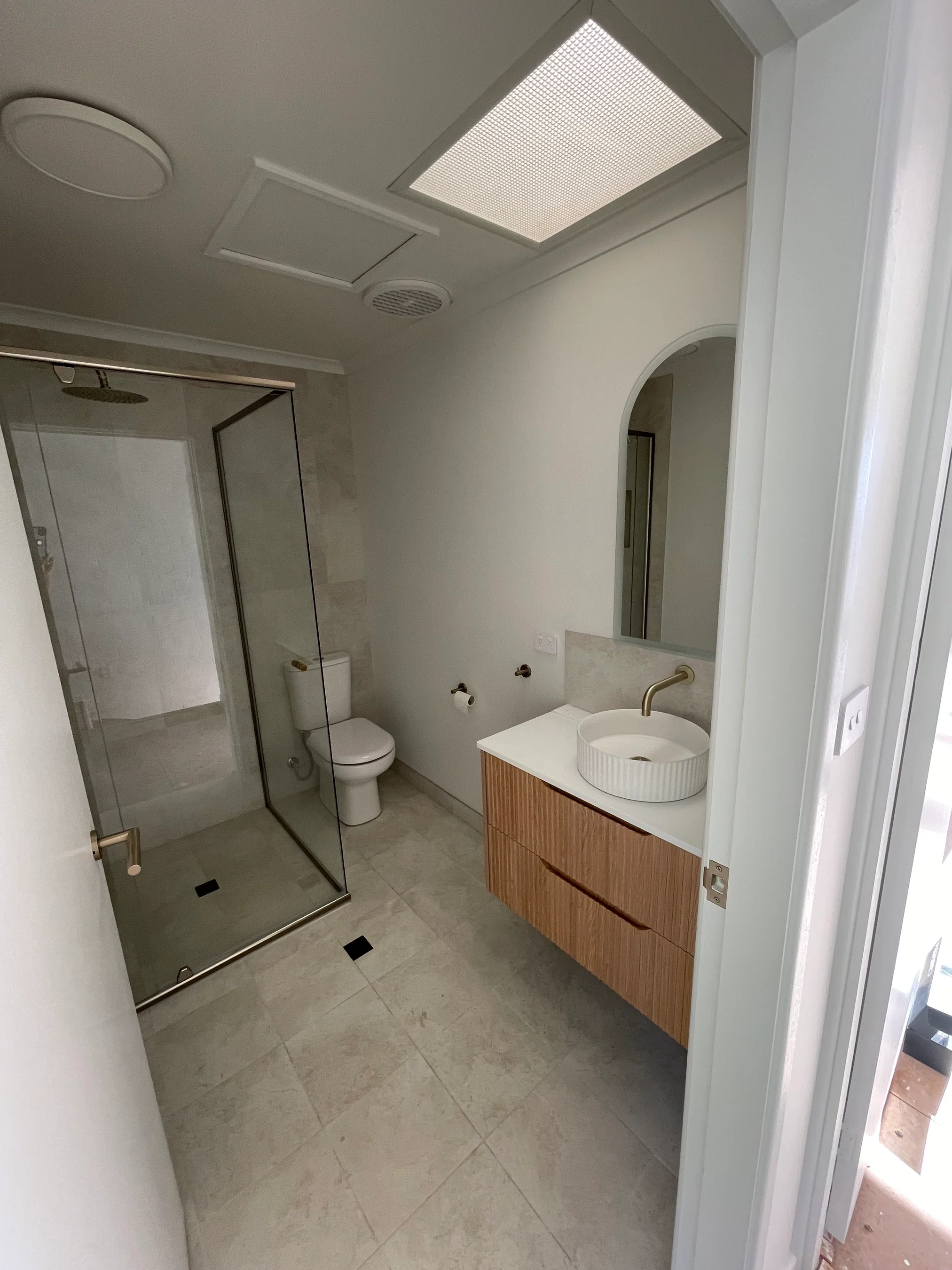 Modern ensuite with floating vanity, gold fixtures and glass shower