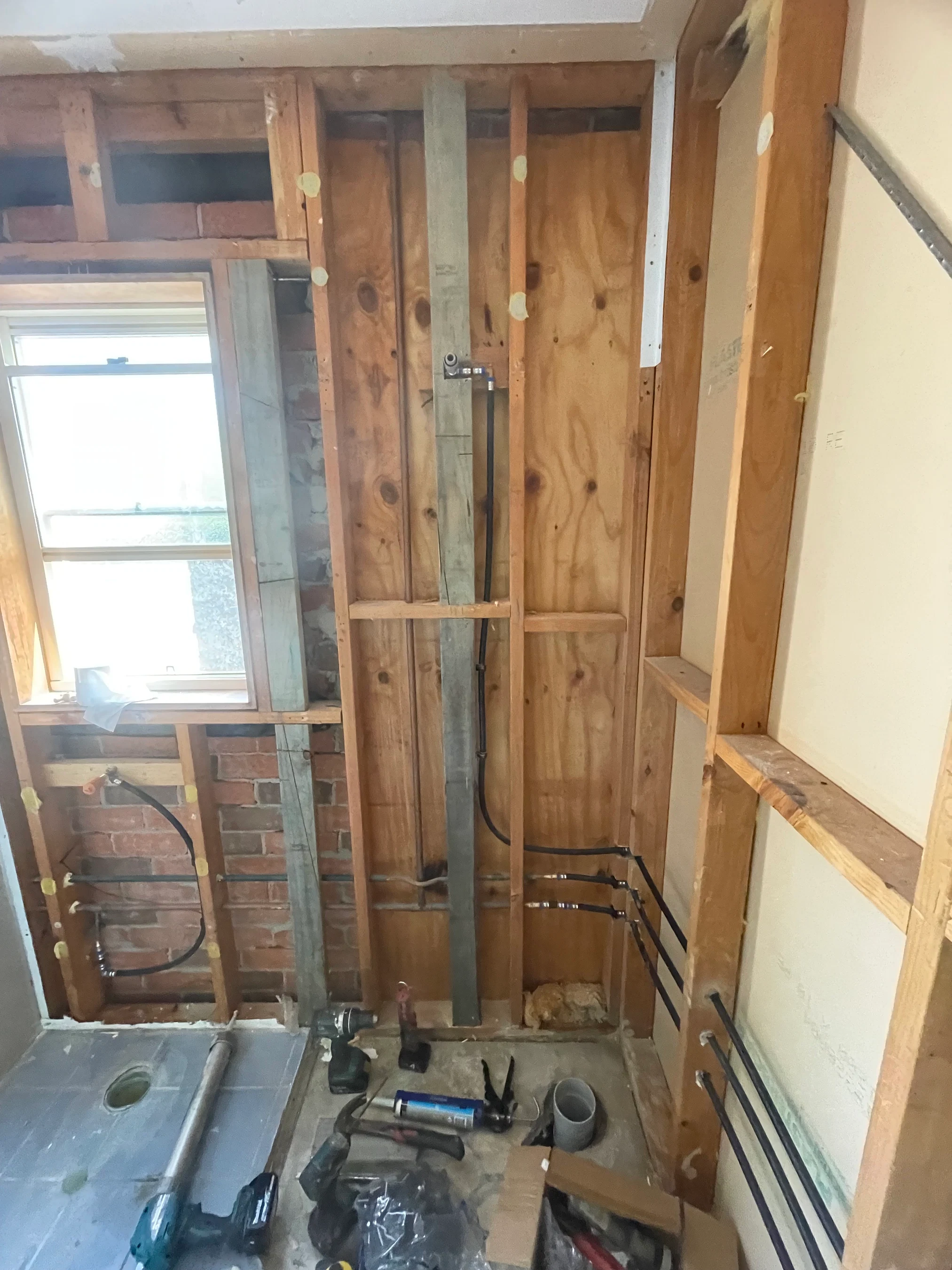 PEX and copper plumbing rough-in in timber wall framing during bathroom renovation