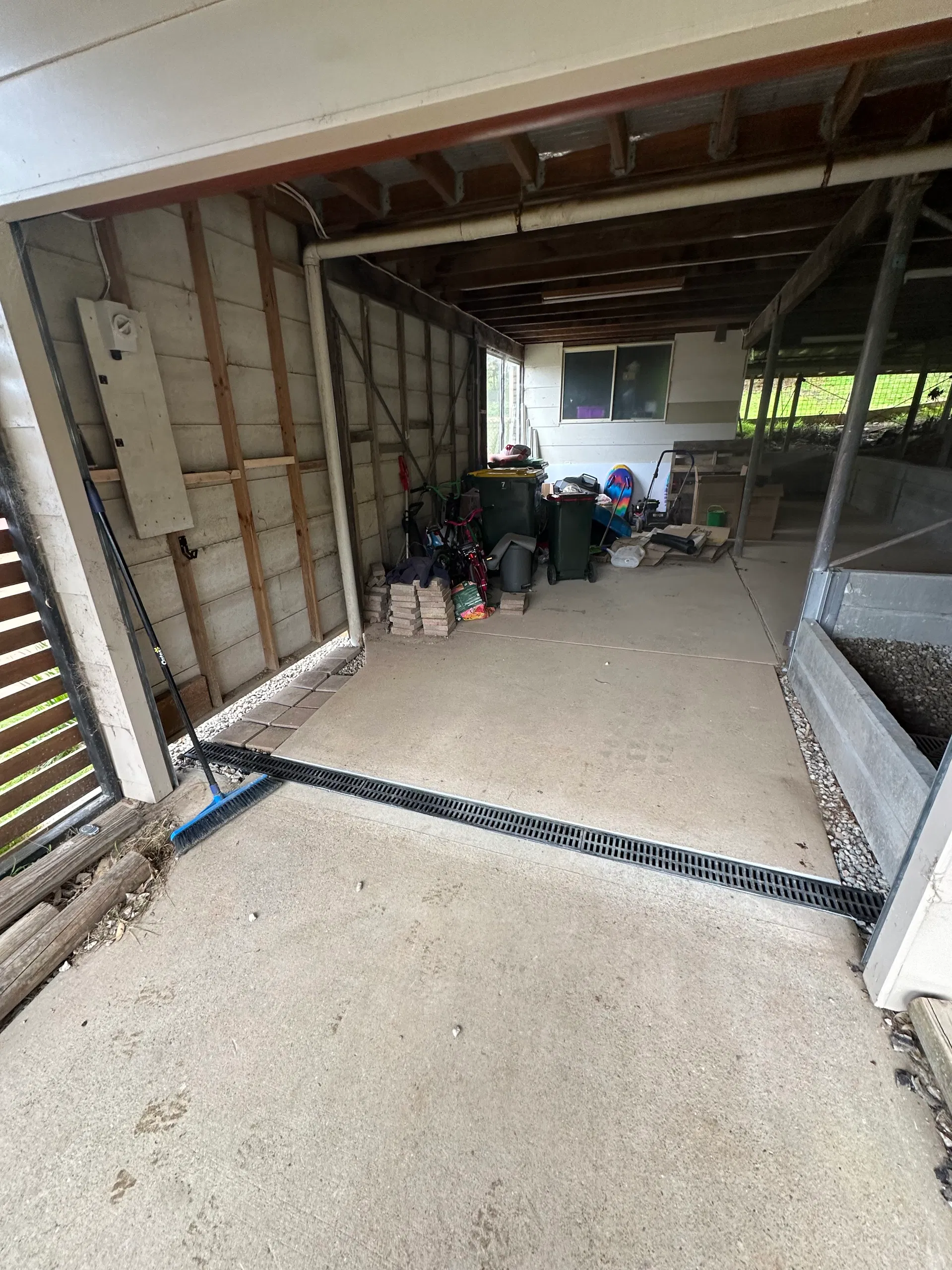 Black drainage grate across concrete carport entry