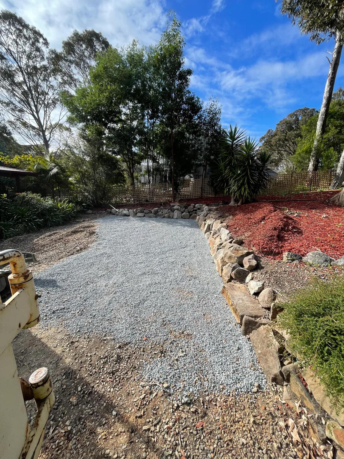 Levelled gravel pad with rock retaining wall and garden mulch