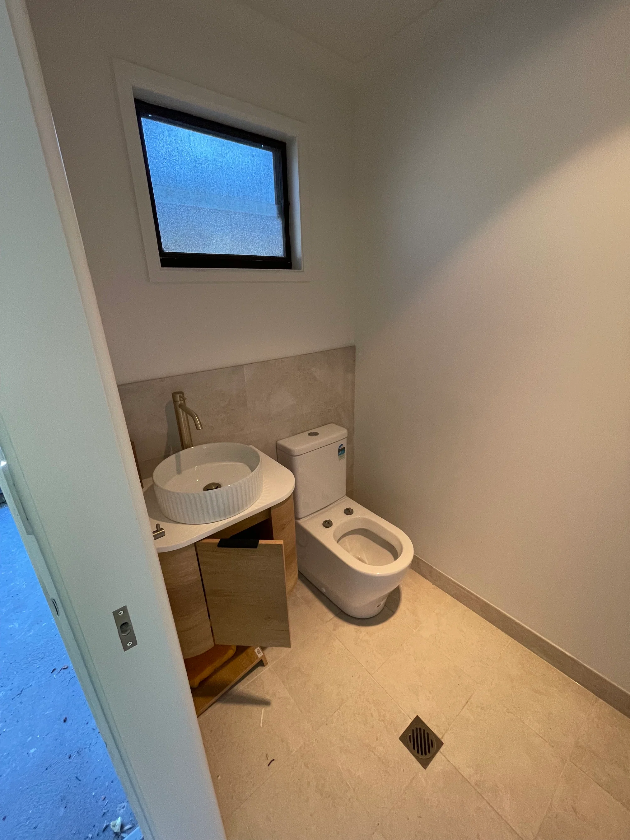 Compact powder room with timber vanity, vessel sink and gold tapware