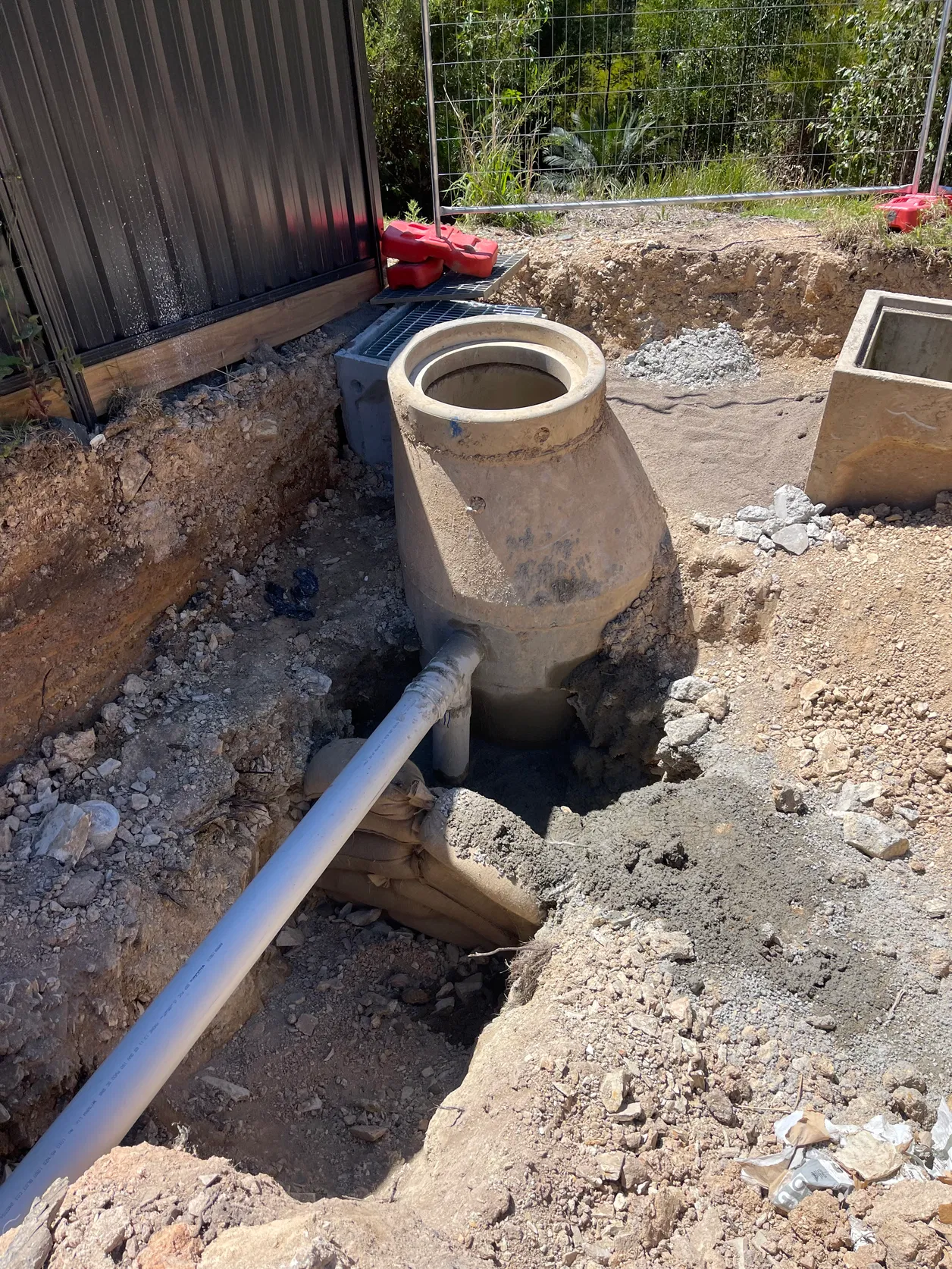Concrete sewer manhole and PVC pipe connection in excavated pit