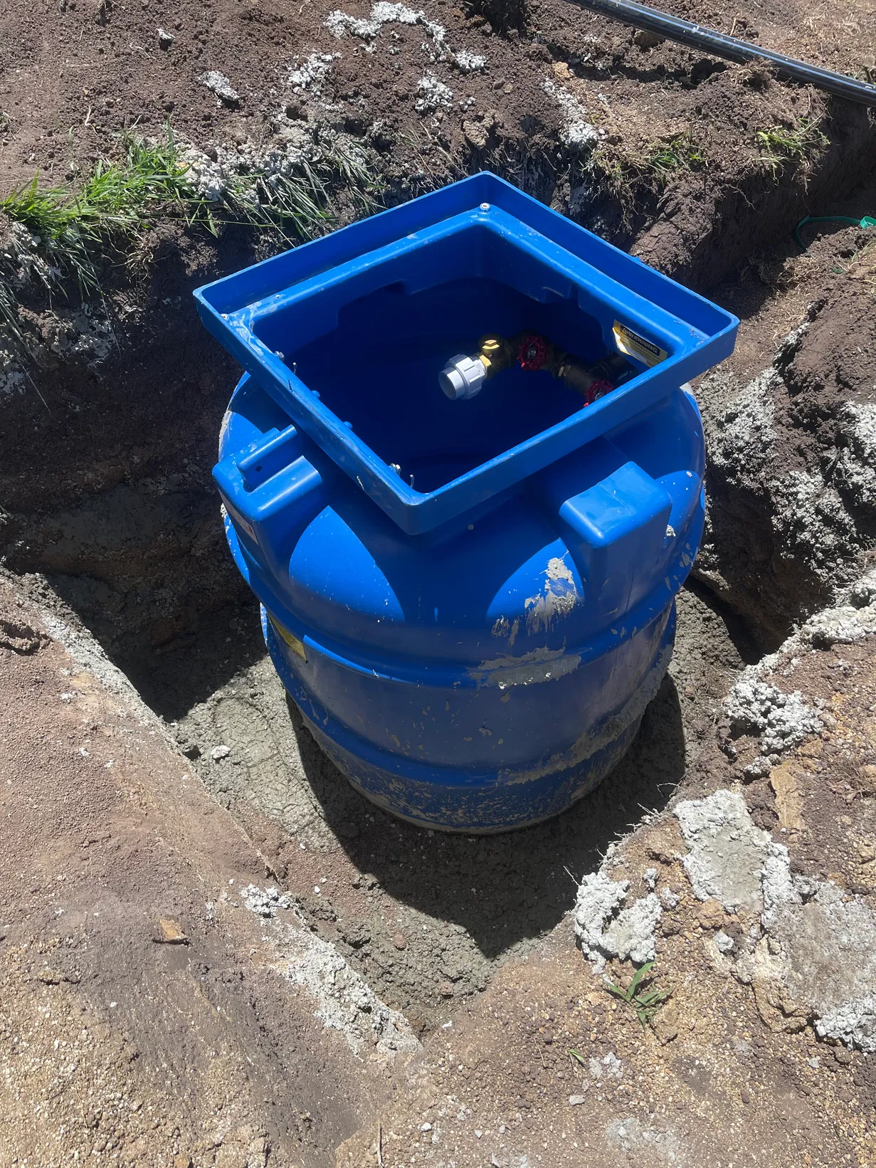 Blue underground utility tank being set in excavated pit
