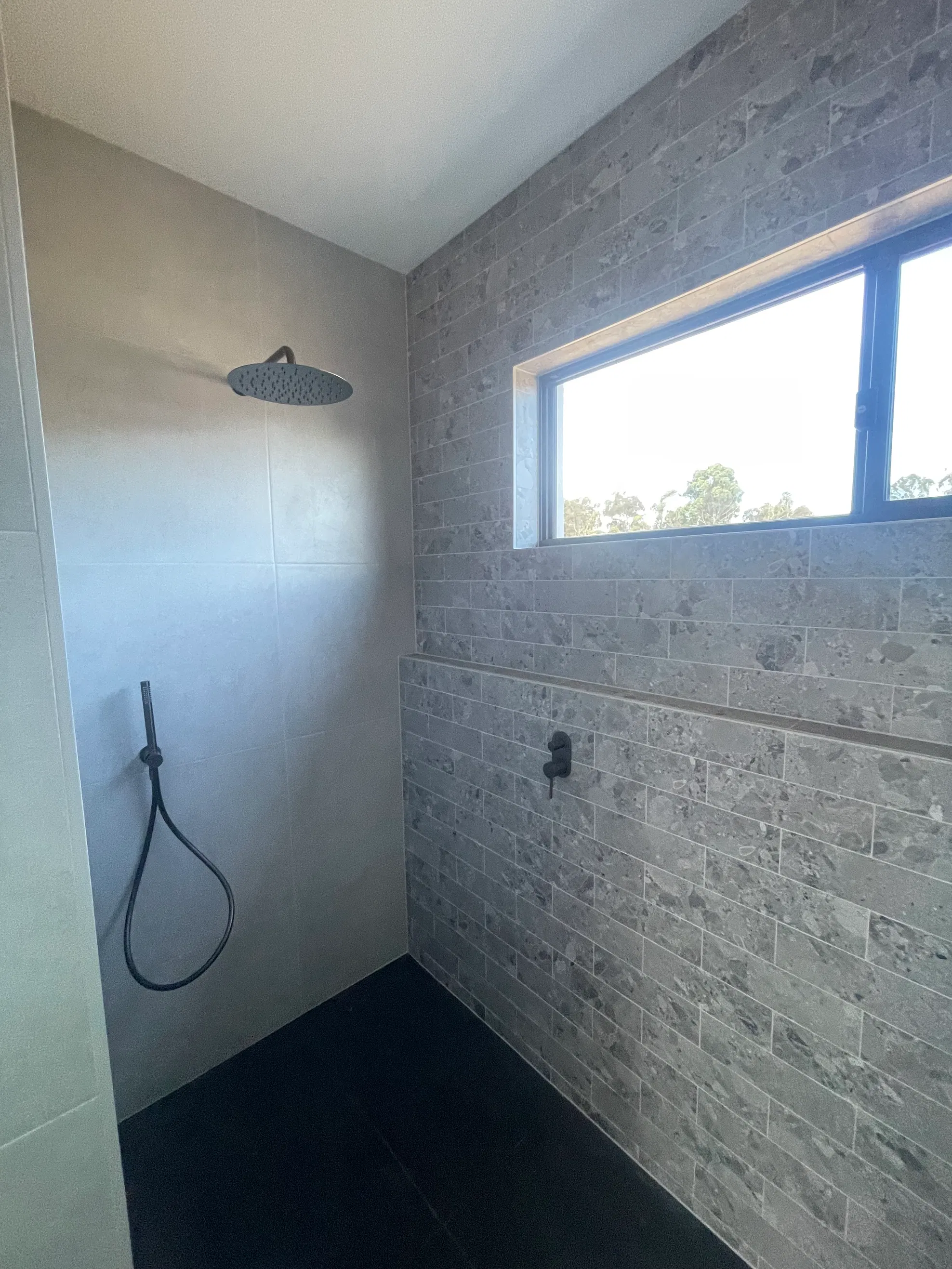 Modern walk-in shower with grey tiles and matte black fixtures